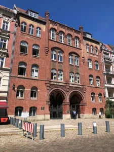 Historic red brick building with arched windows and ornate architectural details on a cobblestone street.