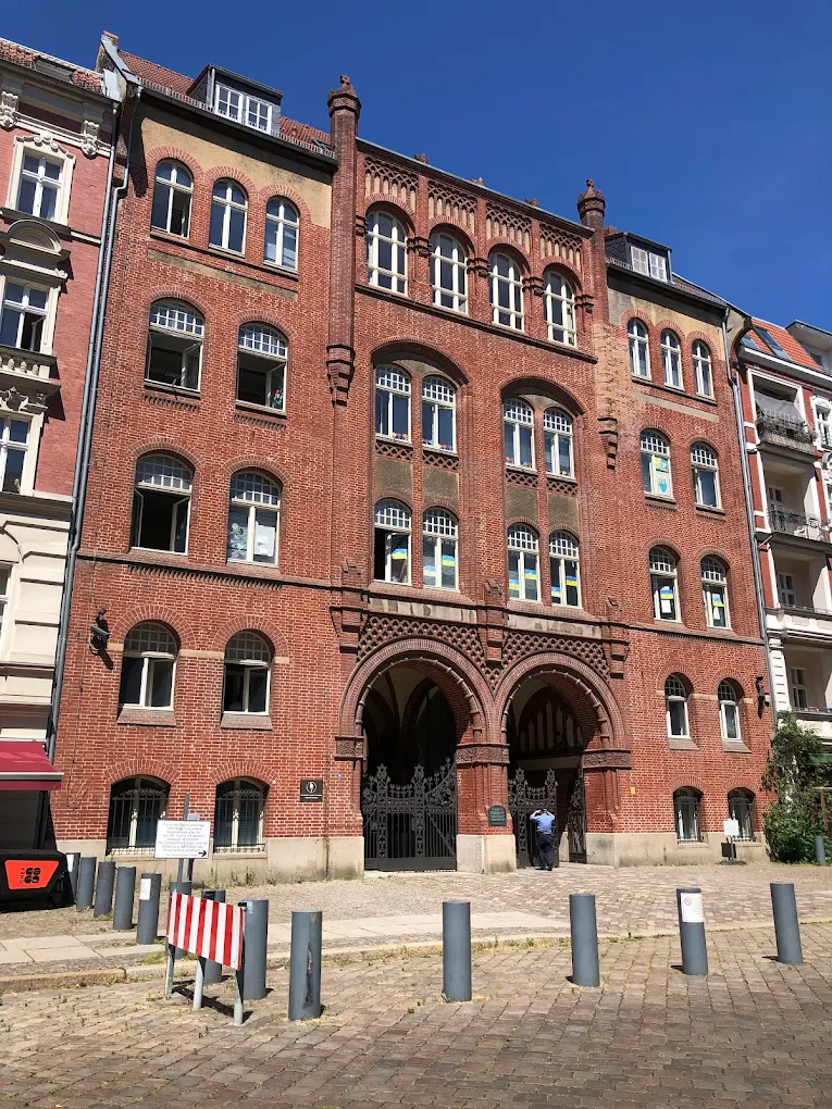 Historic red brick building with arched windows and ornate architectural details on a cobblestone street.