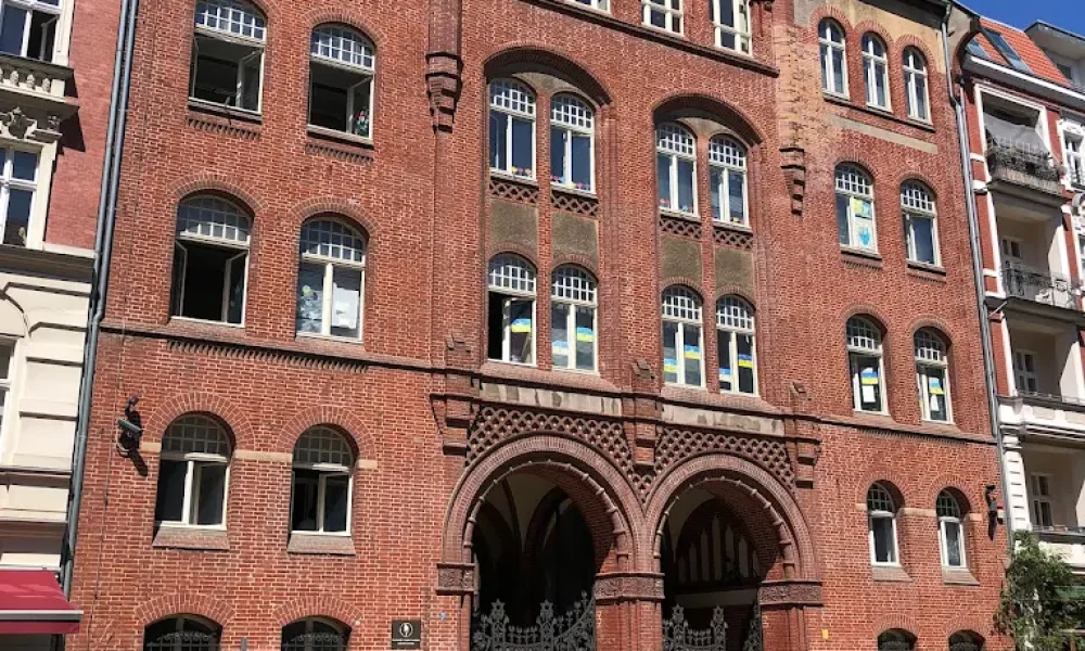 Historic red brick building with arched windows and ornate architectural details on a cobblestone street.